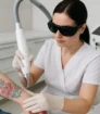 Laserbehandeling op kleurrijke rozentattoo op onderarm door vrouwelijke specialist