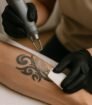 Laserbehandeling op zwarte tribal tattoo op onderarm met rood richtlicht en strakke focus
