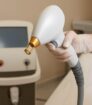 Hand met handschoen houdt laserapparaat met gouden tip in moderne behandelruimte